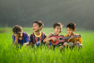 四个男孩笑着坐在草地上白天
